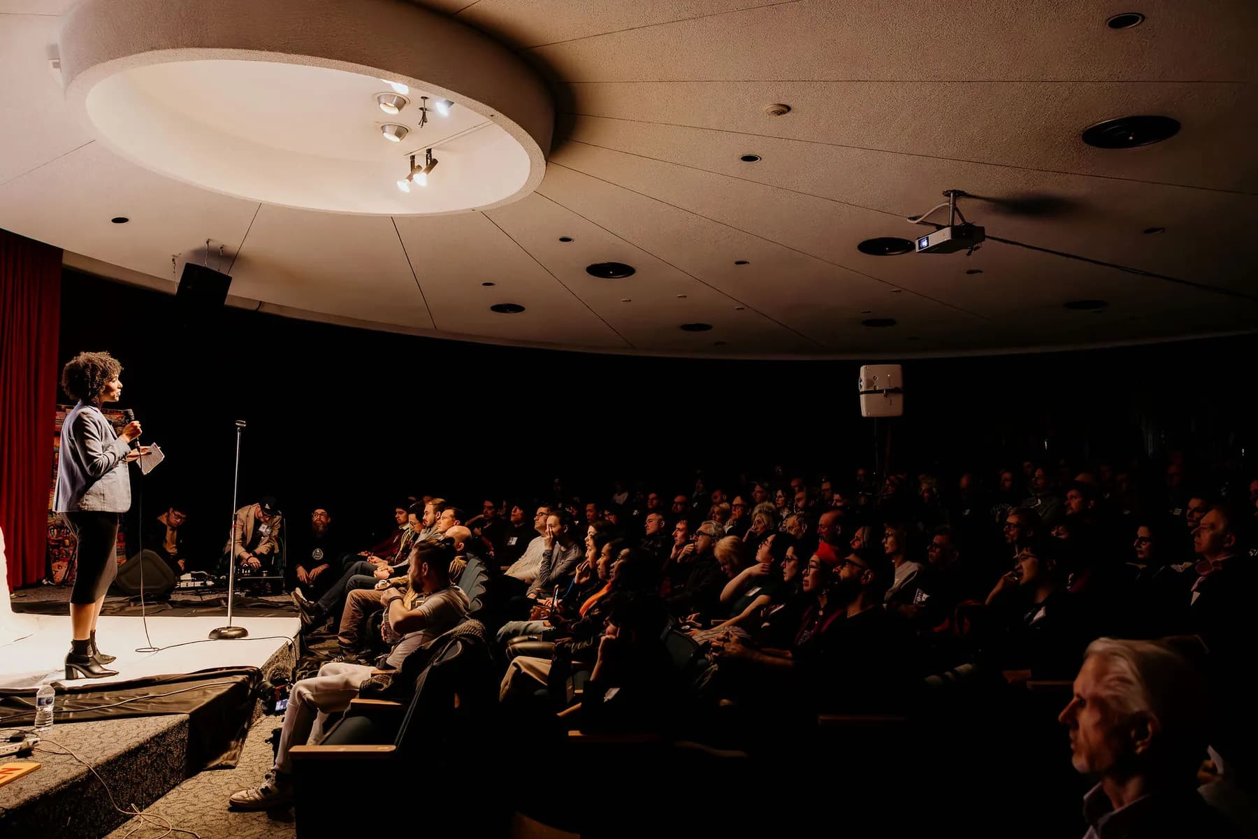 Speaker at the microphone facing a full Space Centre auditorium at a Vancouver AI Meetup
